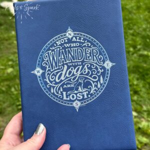 Quote "Not all wander with dogs are lost." on a blue with silver engraving leatherette
